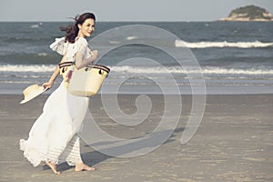 Woman wearing hat and holding bag on beach