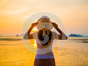 Woman wearing hat with open arms under the sunrise near by the sea