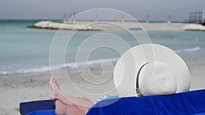 Woman wearing hat relaxing at seashore during summer vacation