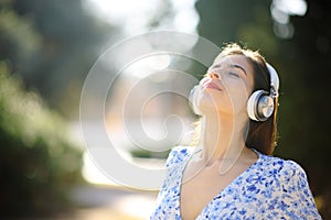 Woman wearing headphone meditating in a park