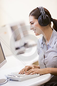 Woman wearing headphones in computer room typing