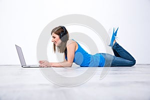 Woman wearing headphones lying on the floor with laptop