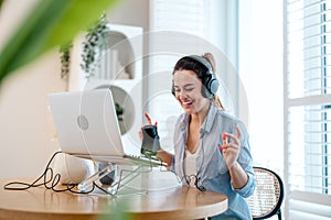 Woman wearing headphones sitting at a desk recording a podcast