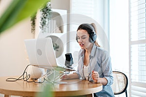 Woman wearing headphones sitting at a desk recording a podcast