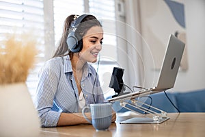 Woman wearing headphones sitting at a desk recording a podcast