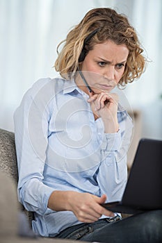 woman wearing headset frowning while using laptop