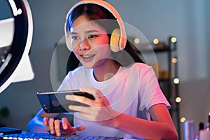 Woman wearing headset and playing online game on smartphone with live broadcasting on internet.