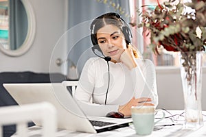 Woman wearing headset and using laptop at home