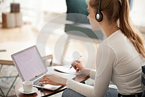 Woman wearing headset using laptop working or studying