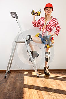 Woman wearing helmet, toolbelt on ladder