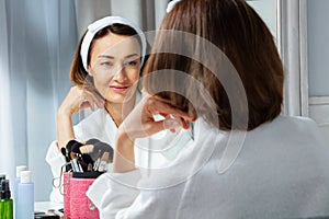 Woman wearing housecoat garment at bathroom look in mirror photo
