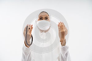 Woman wearing ihram praying al fatihah with prayer beads photo