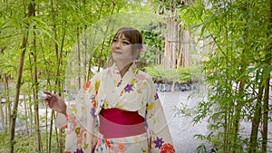 Woman wearing Japanese kimono walking in green bamboo forest