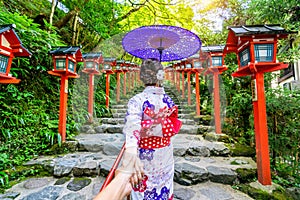Woman wearing japanese traditional kimono holding man`s hand and leading him to Kifune shrine, Kyoto in Japan