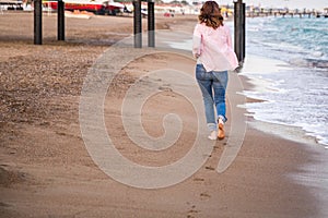 Woman wearing jeans running at sunet on the beach sand