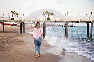 Woman wearing jeans running at sunet on the beach sand