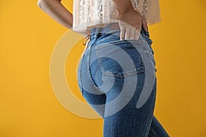 Woman wearing jeans on yellow background, closeup