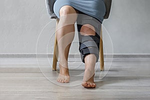 Woman wearing leg brace with adjustable side panels to immobilize and support her knee after surgery