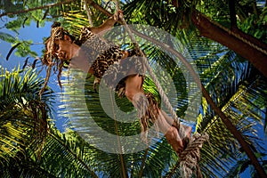 Woman wearing in leopard fur swinging on a rope in jungle