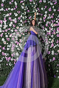 woman wearing long purple dress posing in the flowered garden