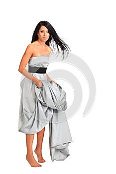 Woman wearing long silver dress stands on tiptoe