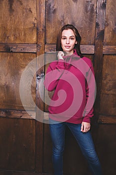 Woman wearing magenta sweatshirt in front of wooden wall