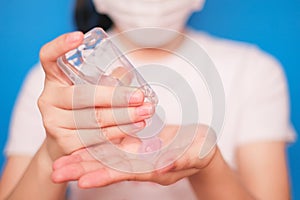 Woman wearing a mask.Cleaning her hands with sanitizer gel