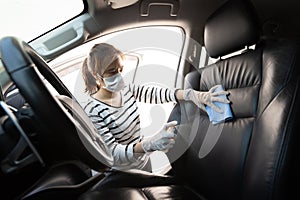 Woman wearing mask,glove,spraying alcohol antiseptic,spray bottle disinfecting,cleaning on backrest,seat in car,safety during