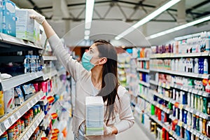 Woman wearing mask and gloves buying baby formula due to Covid-19 or Coronavirus and panic buying.Preparation for a pandemic