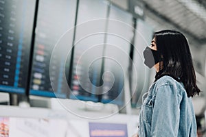 Woman wearing mask looking at flight infomation board display