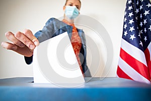 woman wearing mask putting vote in ballot