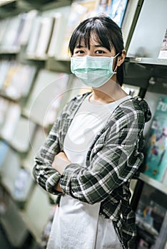 A woman wearing a mask and searching for books in the library