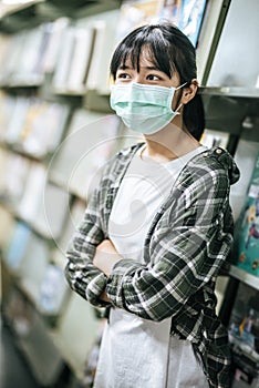 A woman wearing a mask and searching for books in the library