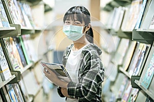 A woman wearing a mask and searching for books in the library