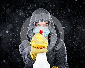 Woman wearing medical mask and cleaning gloves spraying a mist of disinfectant. Serious about keeping clean and virus free