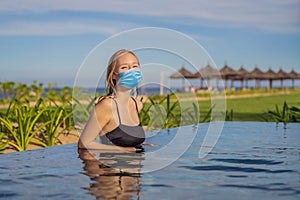 Woman wearing a medical mask during COVID-19 coronavirus relaxing in infinity swimming pool looking at view