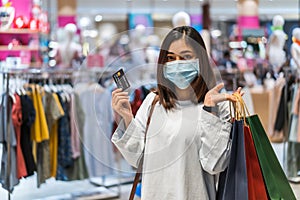 Woman wearing medical mask and holding credit card at shopping mall for prevention from coronavirus Covid-19 pandemic. new