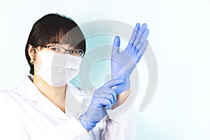Woman is wearing a medical mask in a white uniform, protective blue gloves. Copyspace