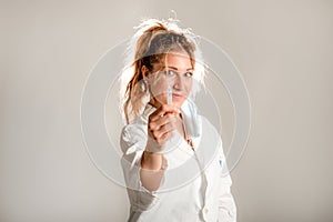 Woman wearing medical uniform showing a phial on a grey background.