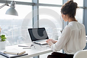 Woman wearing office suit sitting at her workplace, typing, searching new ideas for project. Female writer working with