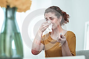Woman wearing orange shirt drying nose suffering from allergy