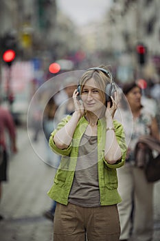 A woman wearing a pair of headphones on a crowded street.