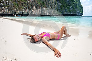 Woman wearing pink bikini laying on beach