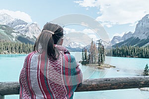 Woman wearing a pink blanket enjoys the scenery at Spirit Island on Maligne Lake in Jasper National Park