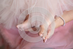 Woman wearing pink tulle dress holding delicately baby girl`s bare feet wearing matching outfit