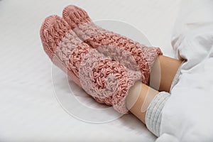 Woman wearing pink warm socks in comfortable bed, closeup