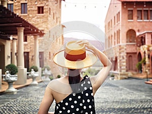 Woman wearing a planter panama hat visiting an Italian style village in summer