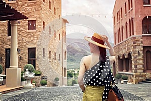 Woman wearing a planter panama hat visiting an Italian style village in summer