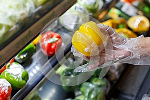 Woman wearing plastic gloves handing a plastic bag with some fruits.shopping concept