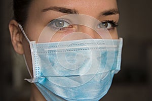 Woman wearing protection face mask against coronavirus on dark background